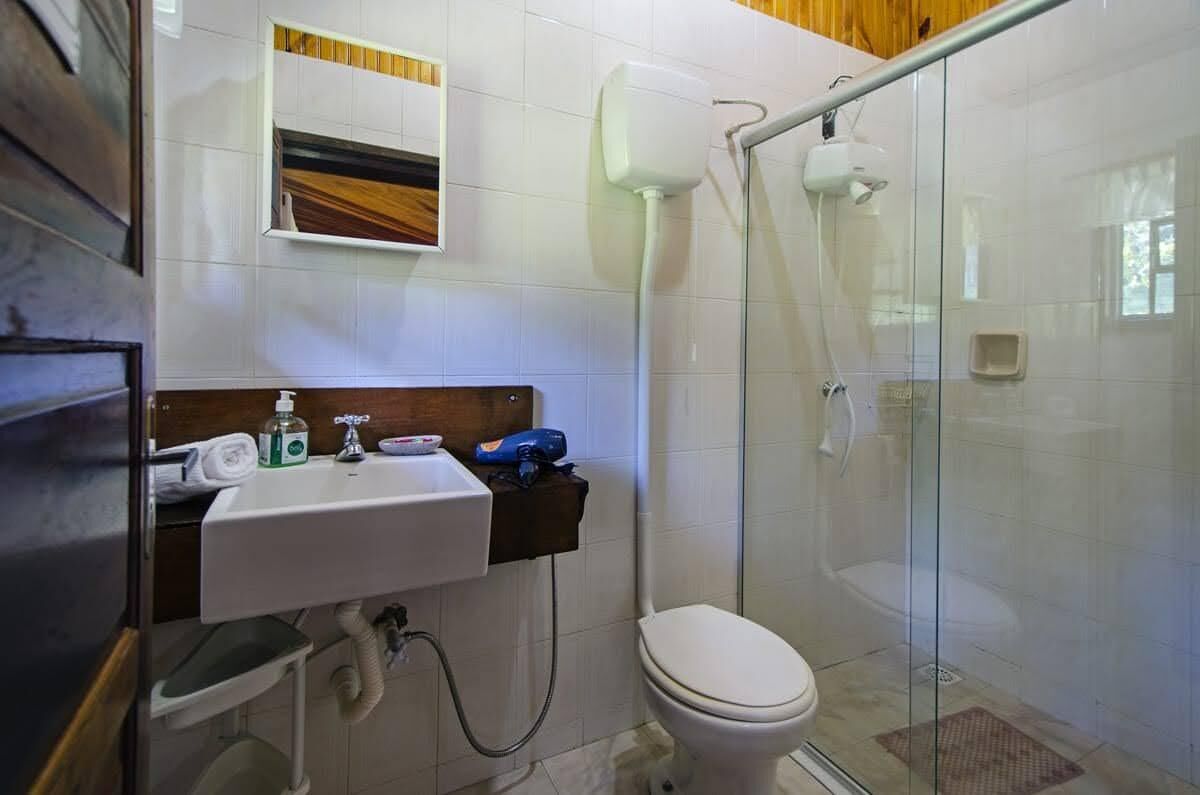 A bathroom with a glass shower enclosure, a white sink, and a toilet.