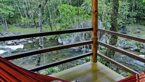 A hammock with a cushion, overlooking a clear stream and lush greenery. - Pousada da Gruta  (Maromba)