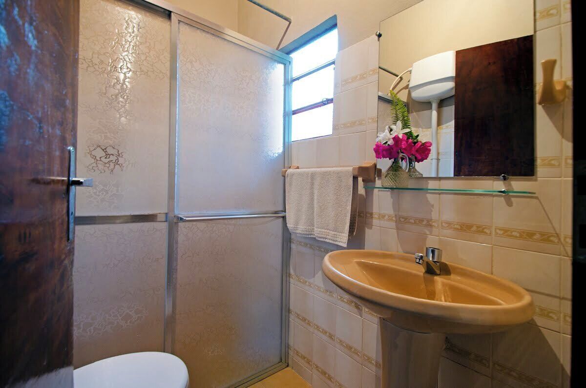 Un baño con inodoro, lavamanos, espejo y cabina de ducha.