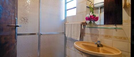 Un baño con inodoro, lavamanos, espejo y cabina de ducha.