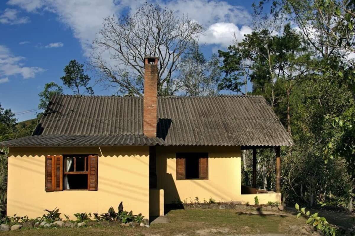 A small, single-story house with a corrugated metal roof and a chimney.