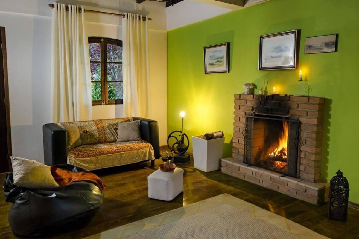 A cozy living room with a sofa, a fireplace, and a window with curtains.