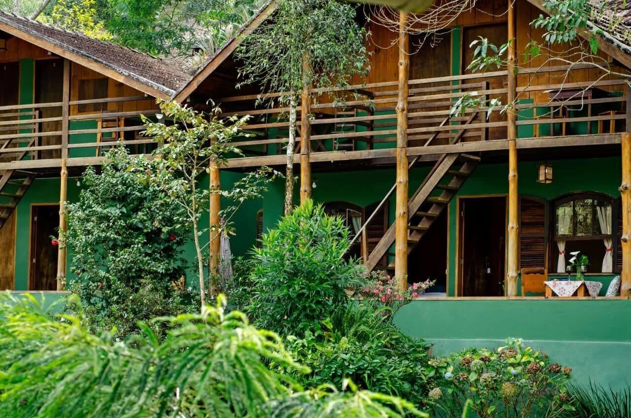A wooden building with a green exterior, a balcony, and a staircase leading to an upper level.