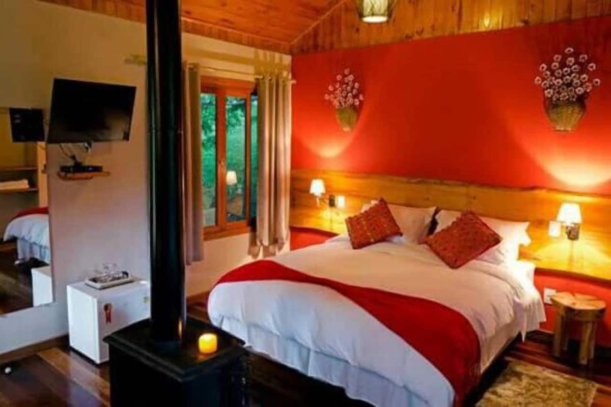 A cozy bedroom with a large bed, a TV, and a fireplace.