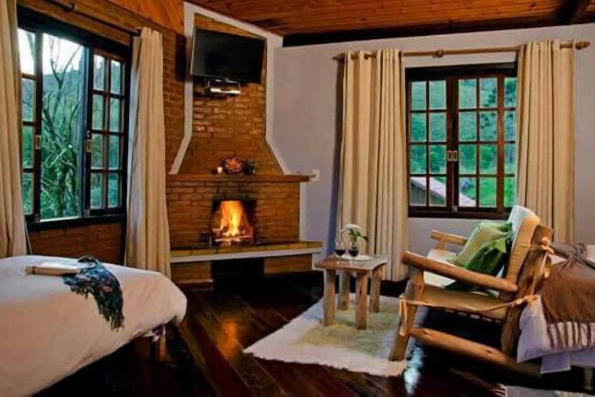 A cozy room with a fireplace, wooden furniture, and large windows.