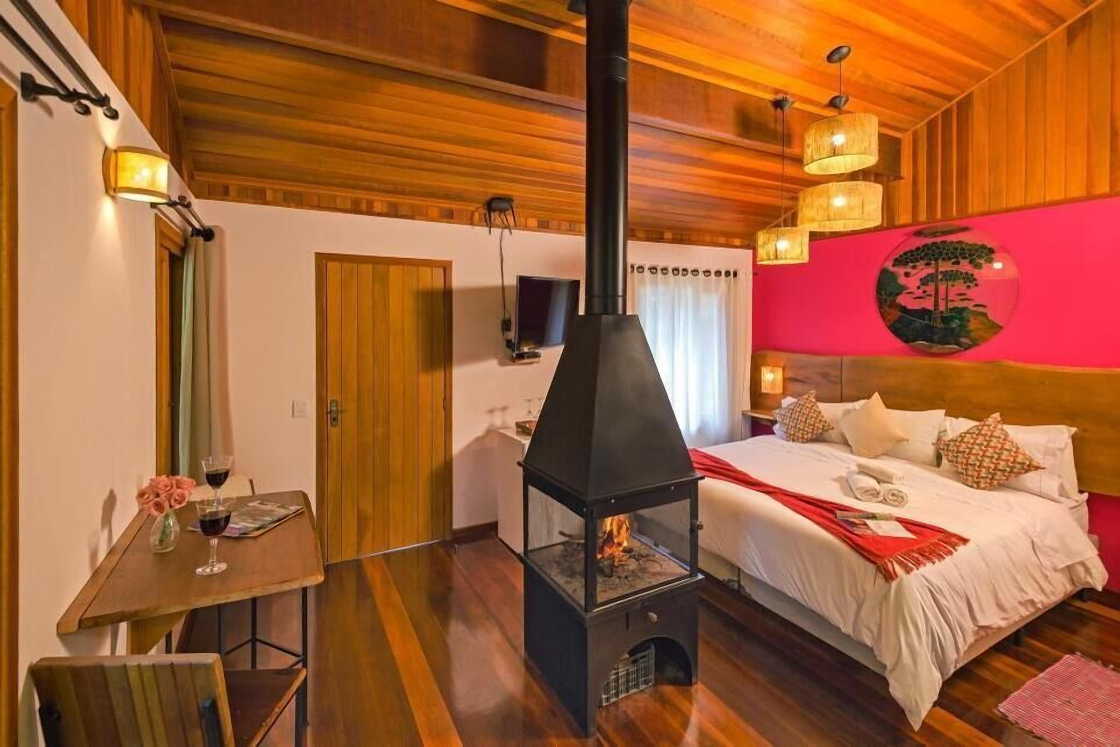 Un cuarto acogedor con una cama, una mesa con bebidas, una chimenea y un cuadro circular en la pared.