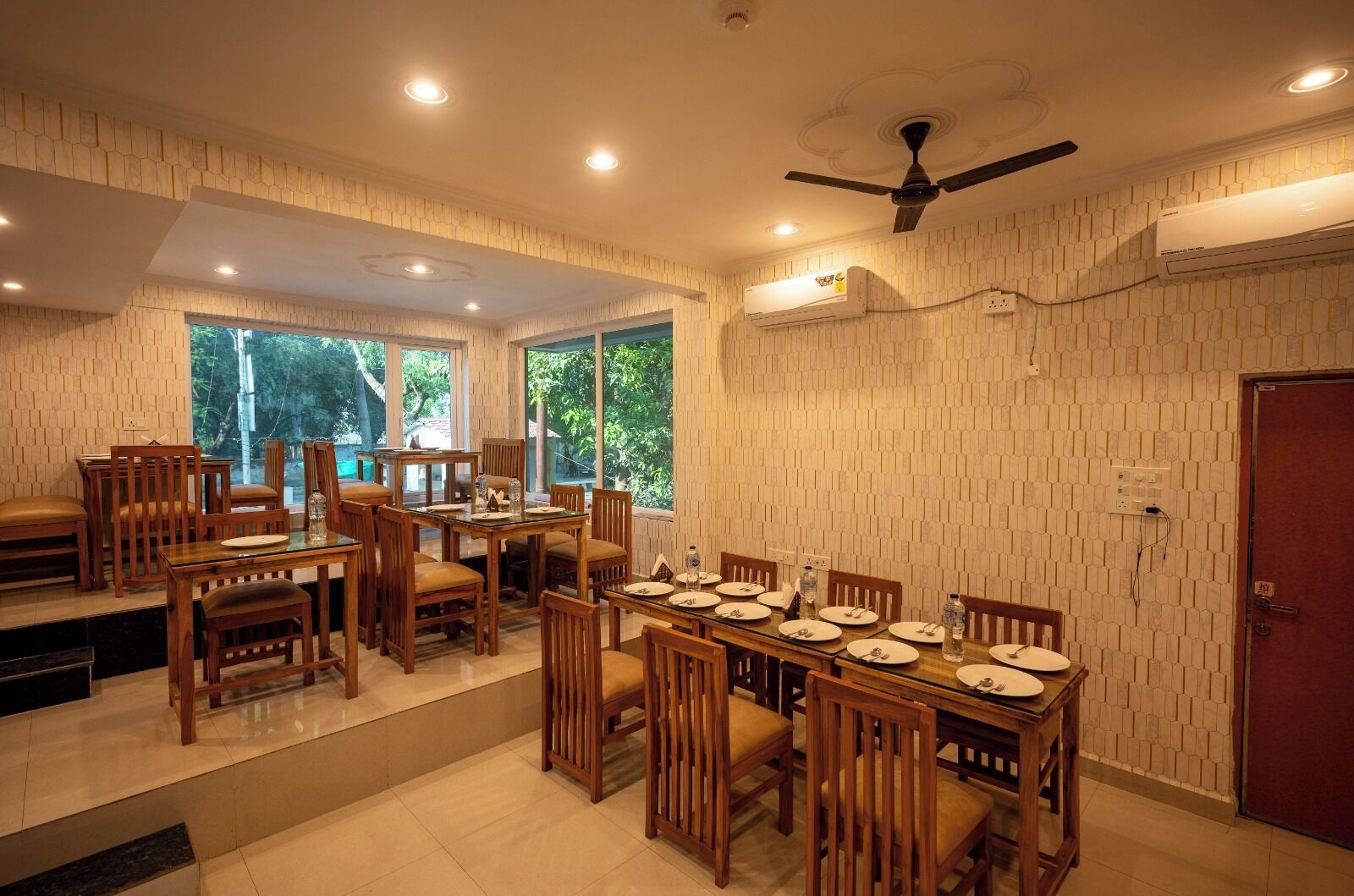 A dining area with wooden furniture, large windows, and an air conditioning unit.