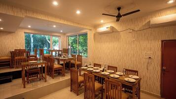 A dining area with wooden furniture, large windows, and an air conditioning unit.