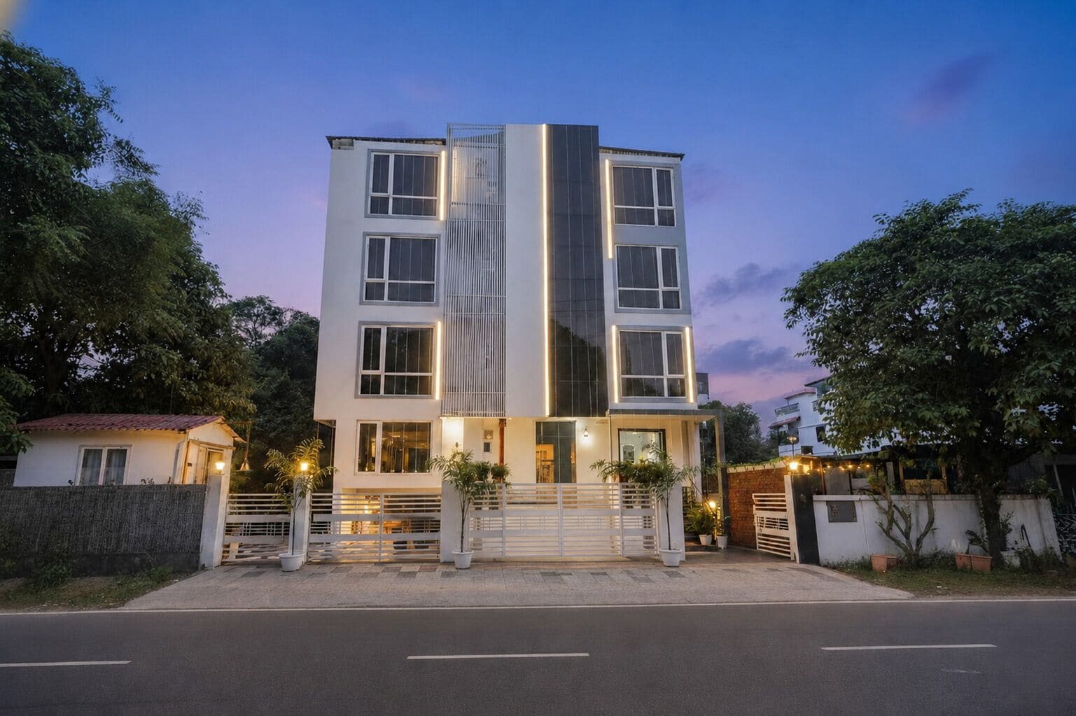 A multi-story building with a modern design, featuring a central vertical glass facade and a gated entrance.