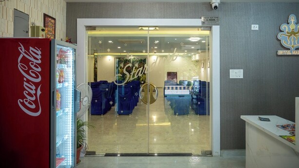 A hotel reception area with a Coca-Cola refrigerator, a glass door entrance, and a reception desk. - Hotel Marine (Varanasi)