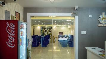 A hotel reception area with a Coca-Cola refrigerator, a glass door entrance, and a reception desk.