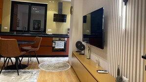 A modern kitchen with a dining area, a flat-screen TV mounted on a striped wall, and a small statue on the counter. - Florenc's Apartment (Farke)