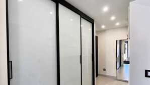 A hallway with a sliding glass door, wooden flooring, and recessed ceiling lights.