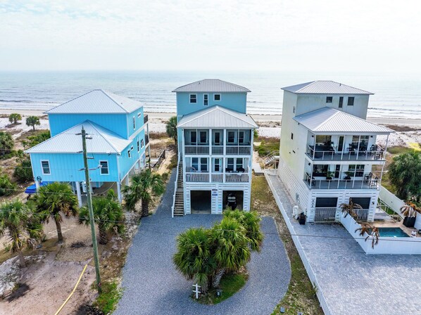 A coastal property with three multi-story buildings, a gravel driveway, and a pool area. - 🌊Beachfront Home with Decks and Views Galore🐾Pet Friendly🐾Sea Forever🌊 (Indian Pass)