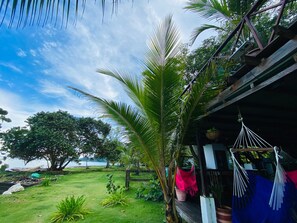 A tropical outdoor area with a hammock, a wooden deck, and a view of the sea. - Hostal Hilltop Capurgana (Capurgana)