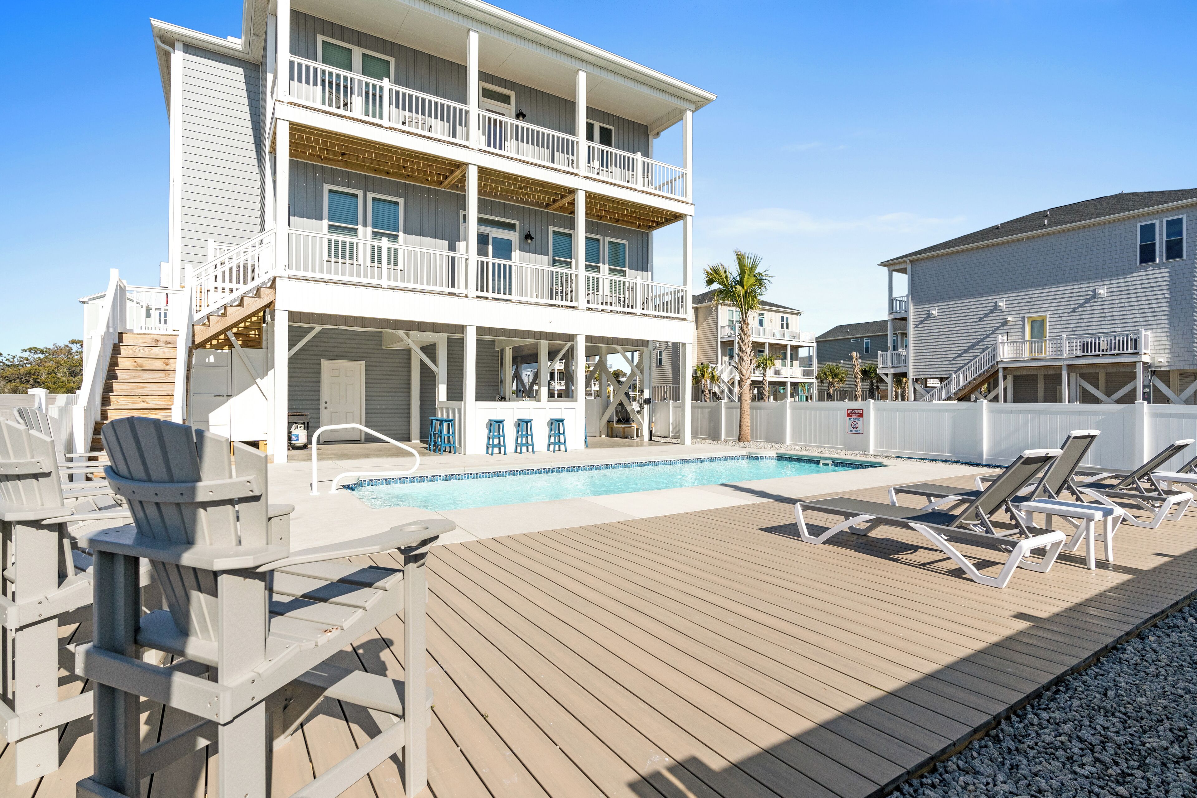 A two-story building with a pool, outdoor seating, and a deck.