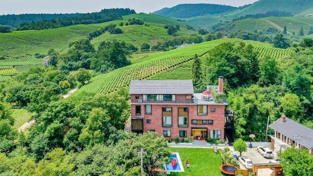 A two-story building with a modern design, surrounded by lush green vineyards and hills. - YOUTEA Holiday Villa (Huzhou)