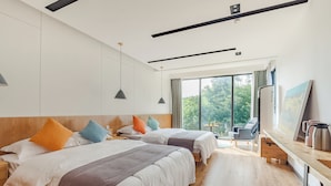 A hotel room with two beds, a desk with a kettle, and a large window offering a view of trees. - YOUTEA Holiday Villa (Huzhou)
