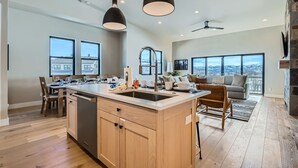 A spacious kitchen with a large island, wooden cabinets, and pendant lighting.