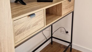 Un mueble bajo de madera con televisor de pantalla plana, un control remoto y un cajón.