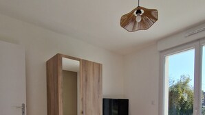 Un dormitorio con una cama grande, un armario, un televisor y una ventana con vistas al exterior.