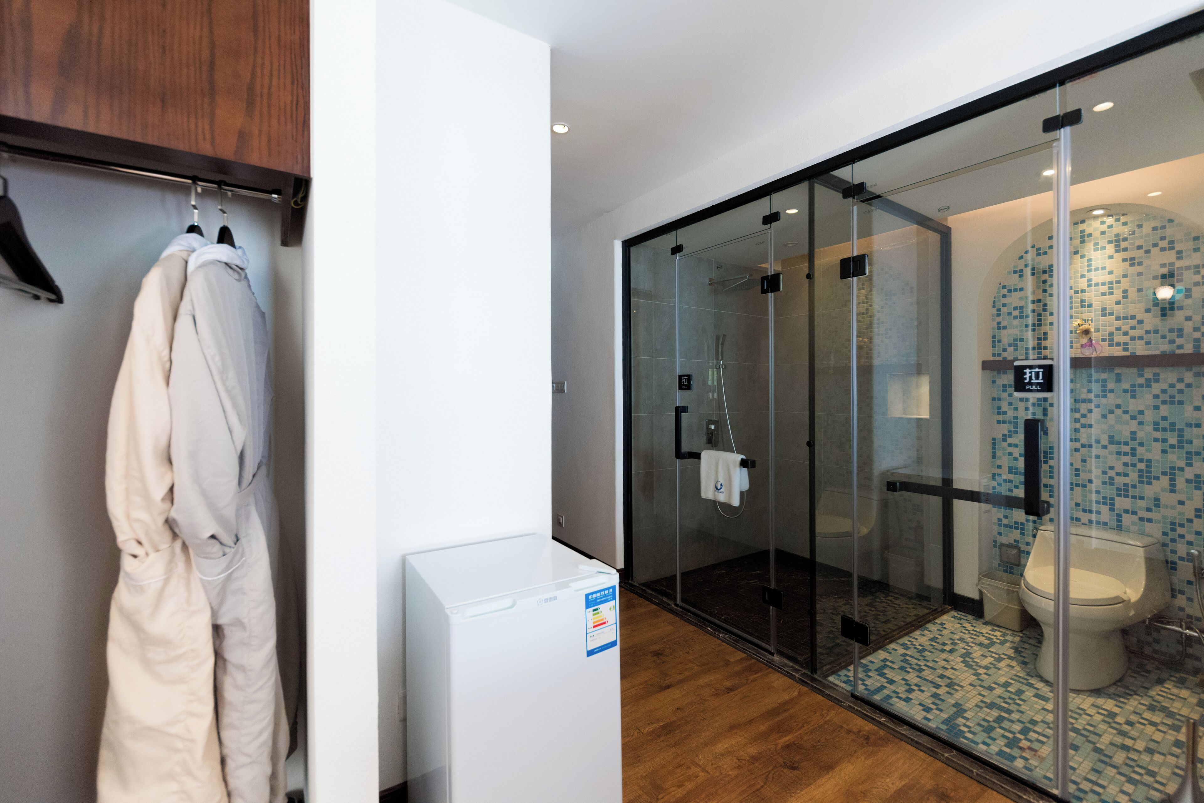 A modern bathroom with a glass shower enclosure, a toilet, and a white washing machine.