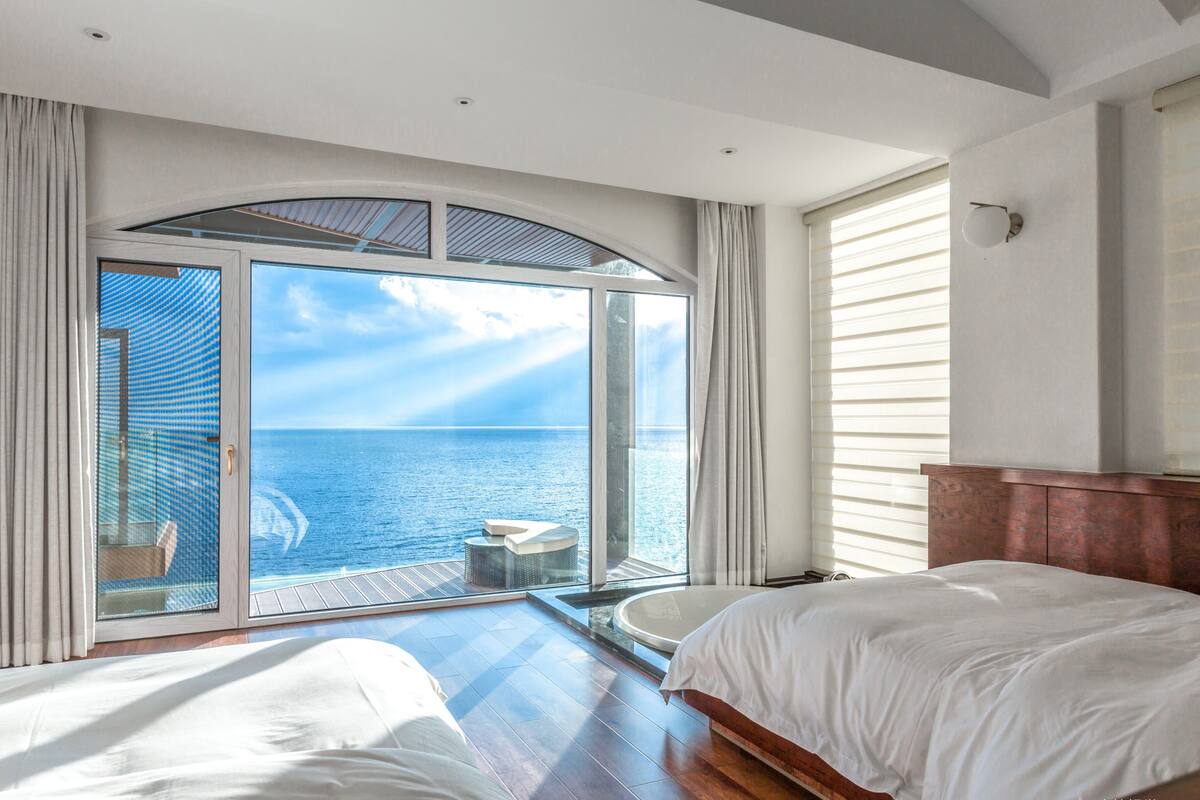 Une chambre dotée d’une grande porte-fenêtre coulissante donnant sur un balcon avec vue sur la mer.