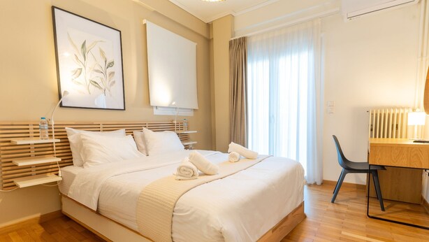 A hotel room with a large bed, bedside tables, a desk, and a chair. - Acropolis Central Living (Athina)