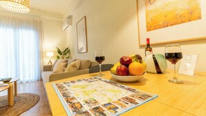 A cozy living room with a wooden table, a bowl of fruit, two wine glasses, and a framed picture on the wall. - Acropolis Central Living (Athina)