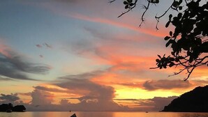 A sunset over a calm body of water with two boats anchored. - Hostal Hilltop Sapzurro (Sapzurro)