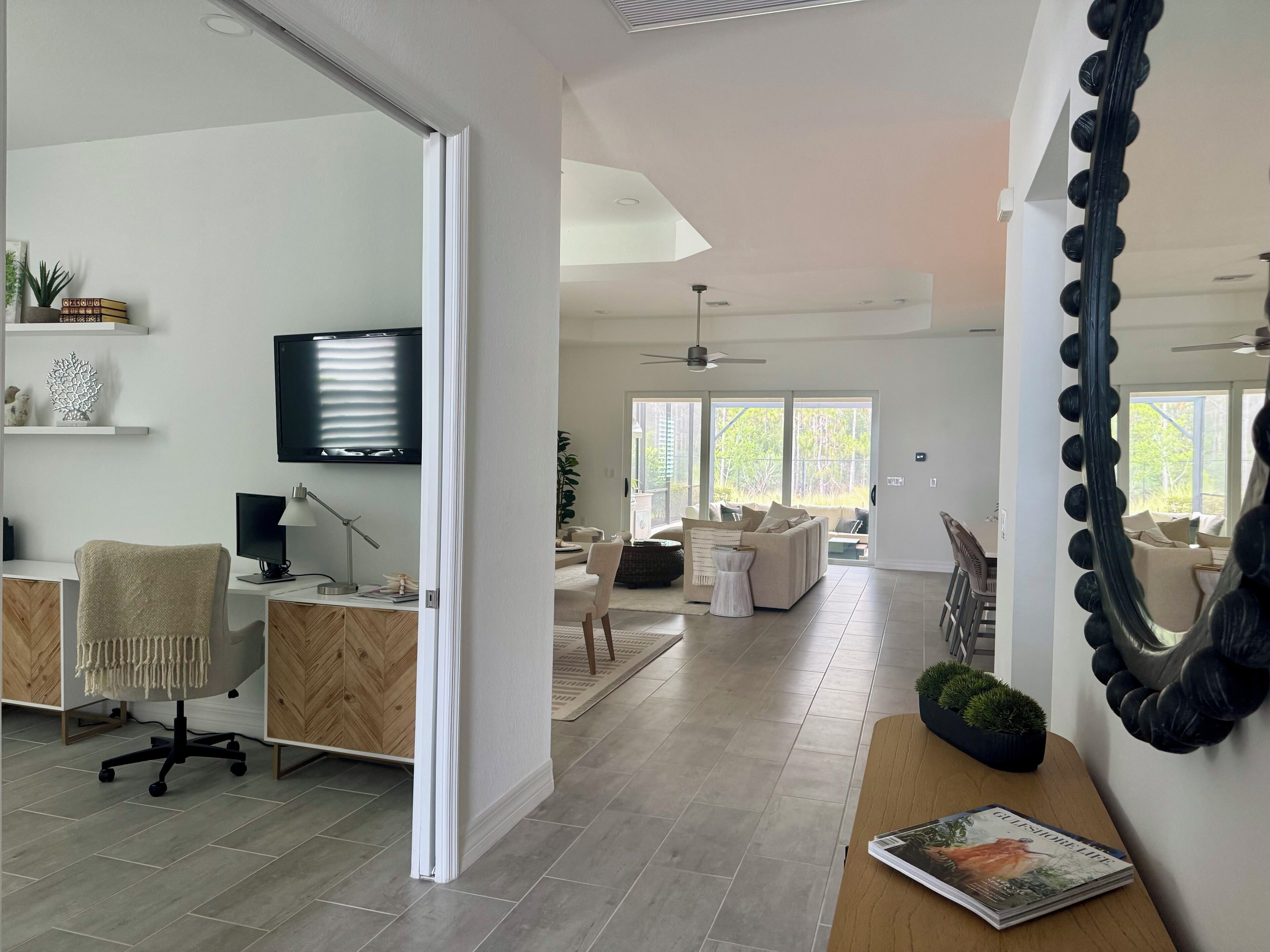 Un salon moderne avec un téléviseur, un bureau avec un ordinateur et un canapé.