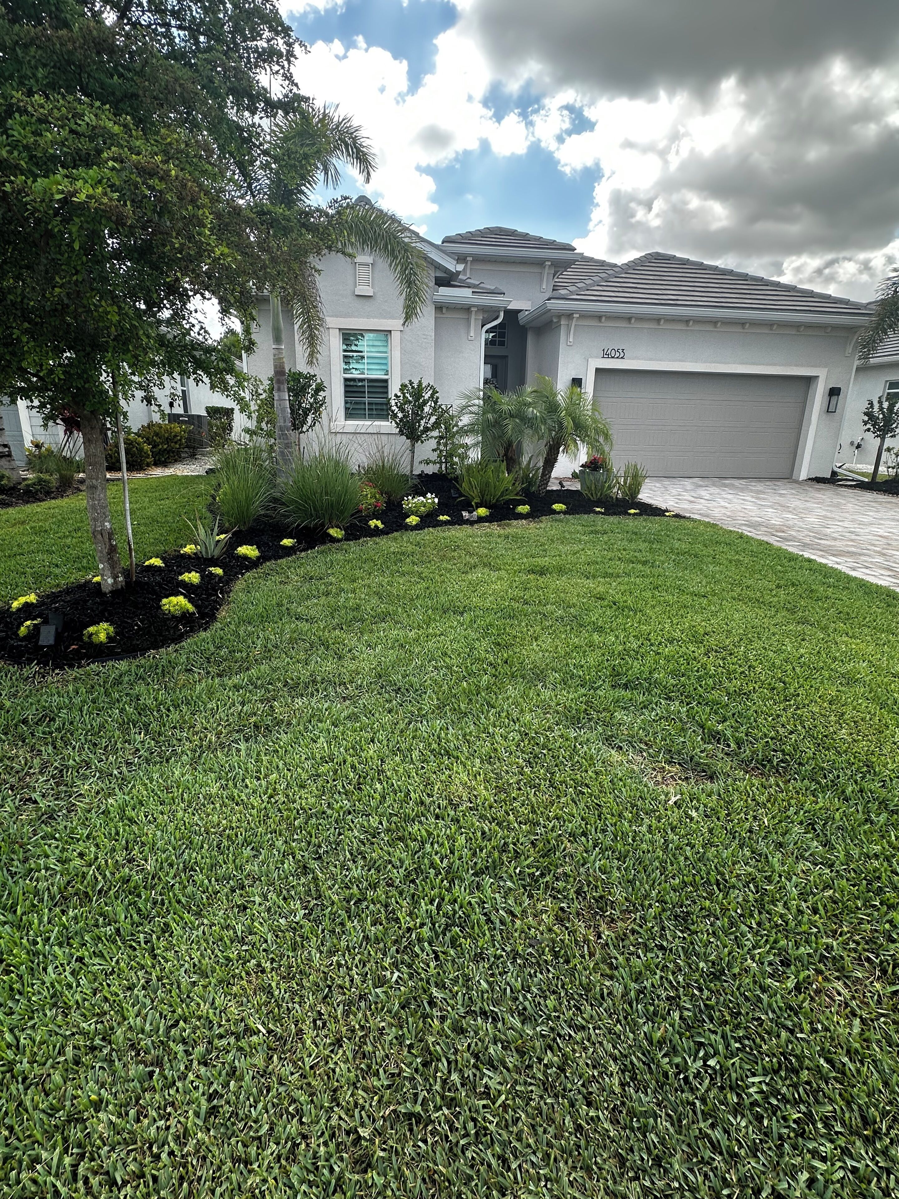 A residential house with a well-maintained lawn, a driveway, and a garage.