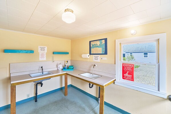 Une petite salle de bain propre, avec deux lavabos, des toilettes et une fenêtre donnant sur un immeuble.
