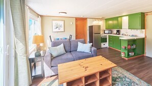 A compact living space with a sofa, a small table, a kitchenette, and a dining area.