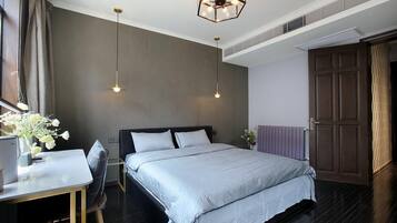 Un dormitorio moderno con una cama grande, un escritorio con silla y un jarrón decorativo con flores.