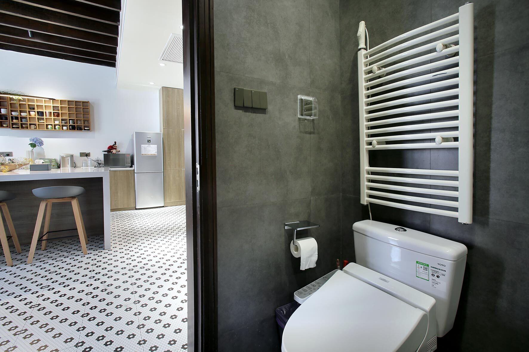 A modern bathroom with a toilet, a towel rack, and a shower area.