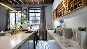 A modern kitchen with a long countertop, a built-in oven, and a wooden shelf above the sink. - Hills boutique (Shanghai)