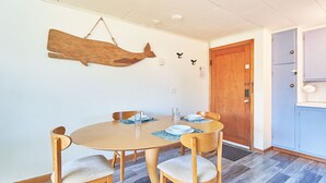A dining area with a round table, four chairs, and a wooden fish decoration on the wall. - PICKLEBALL! Walk to Beach, Fireplace, BBQ (ANC#9) (Long Beach)