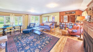 A spacious living room with a large rug, a sofa, a coffee table, and a bookshelf.