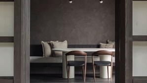A modern dining area with a dark wooden partition, a bench, two chairs, and pendant lighting. - The Lodge - Luxury Design Villa in Oostduinkerke (Koksijde)