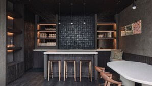 A modern kitchen with a central island, bar stools, and pendant lighting. - The Lodge - Luxury Design Villa in Oostduinkerke (Koksijde)
