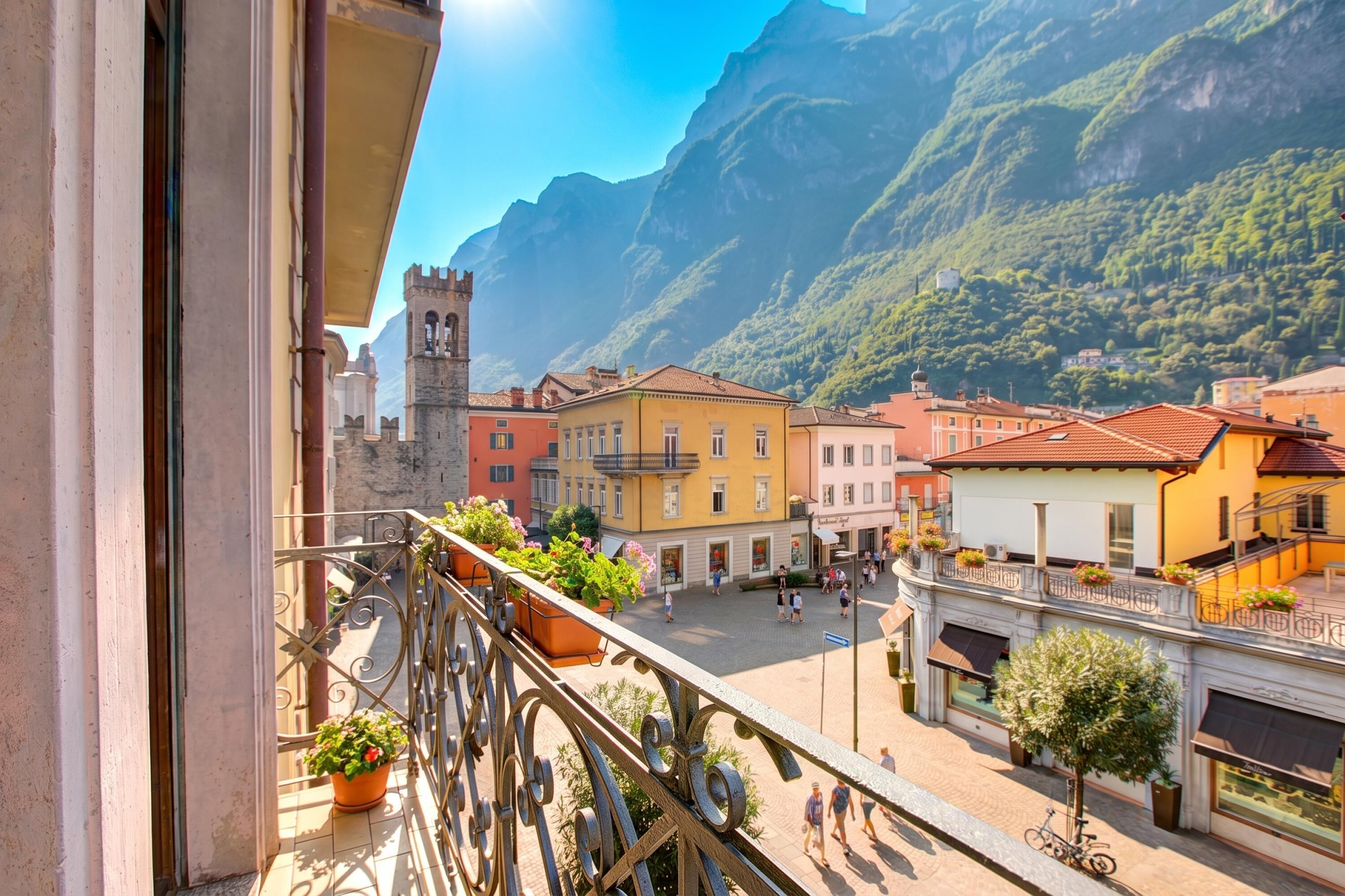A balcony with a view of a town square, buildings, and mountains.