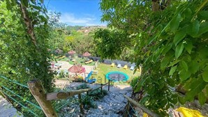 A staircase leading to a pool area surrounded by greenery, with a view of a village in the distance.
