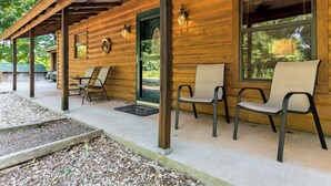A wooden cabin with a covered porch, two chairs, a table, and a door with a wreath.