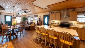 A spacious kitchen with wooden cabinets, a central island, and a dining area with wooden chairs.