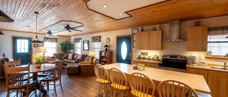 A spacious kitchen with wooden cabinets, a central island, and a dining area with wooden chairs.