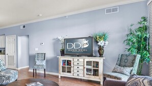 A living room with a sofa, chairs, a TV, and a cabinet.