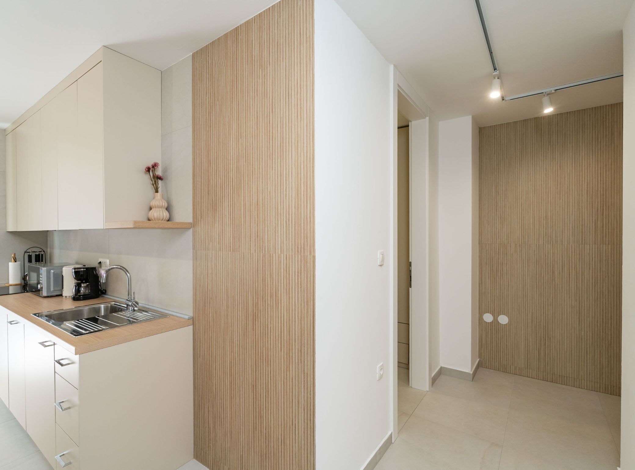 A modern kitchen with white cabinets, a wooden countertop, and a built-in sink.