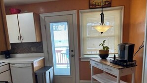 Cocina compacta con lavavajillas, cafetera y una planta en el alféizar de la ventana.