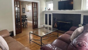 Una sala de estar con una mesa de centro de vidrio, sofá de cuero y chimenea.